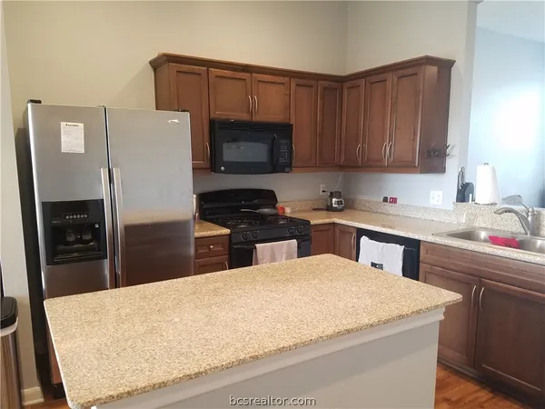 a kitchen with stainless steel appliances granite countertop a sink refrigerator and microwave