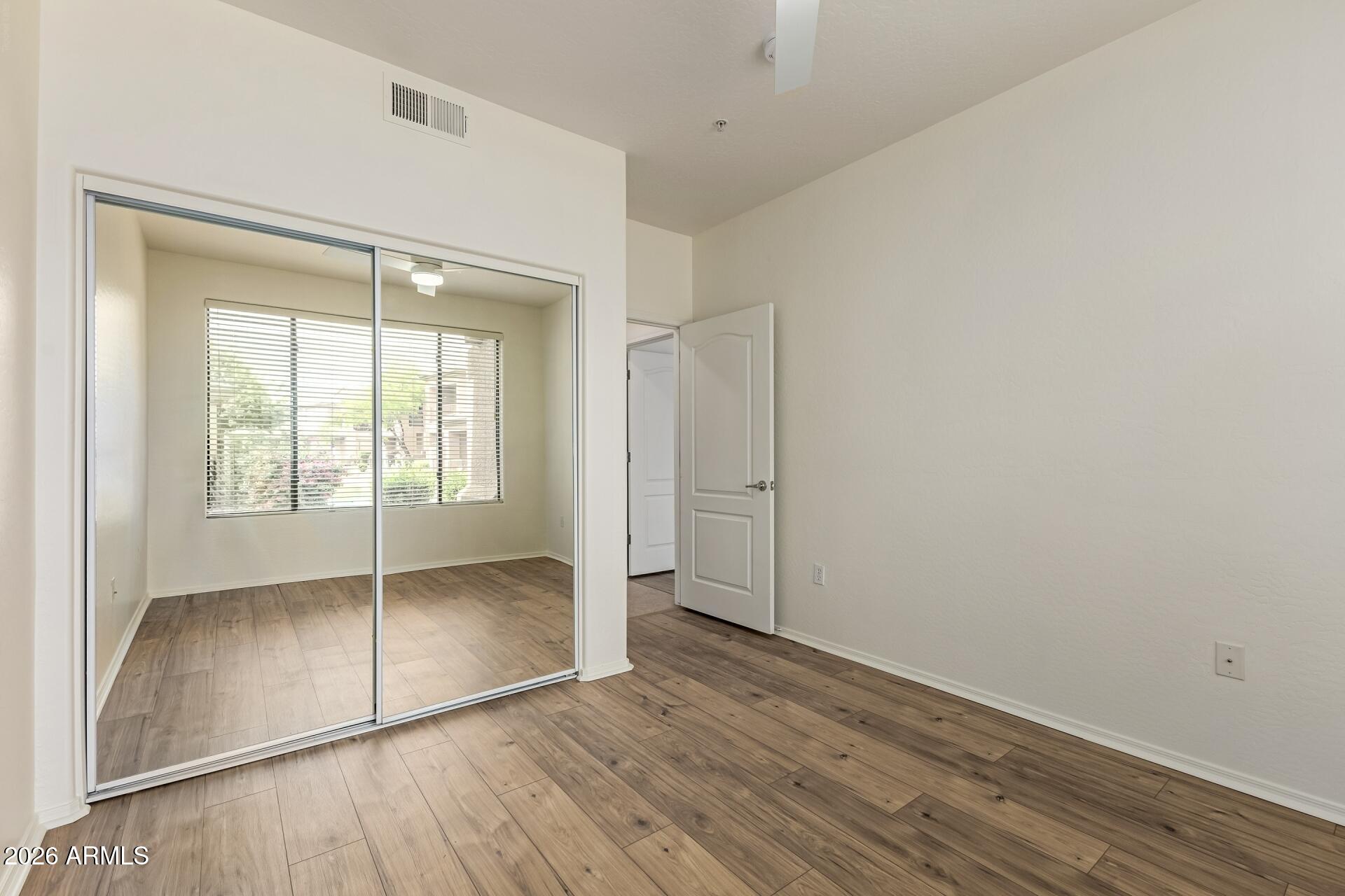 705 West Queen Creek Road, Unit 1167 Chandler, AZ 85248 - Photo 22 of 31 an empty room with wooden floor and windows