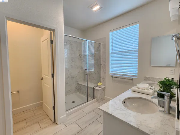 a spacious bathroom with a granite countertop sink a mirror and shower