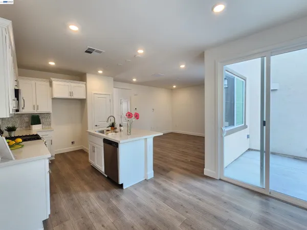 a kitchen with kitchen island granite countertop wooden floors and white cabinets