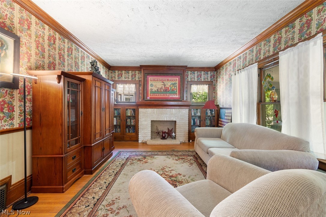Living room featuring light wood-type flooring, ornamental molding, and a textured ceiling