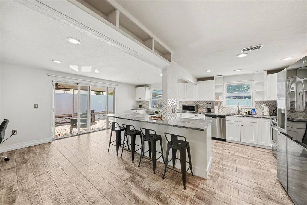 8828 Carmen Lane Port Richey, FL 34668 - Photo 11 of 28 a kitchen with a dining table chairs wooden floor appliances and cabinets