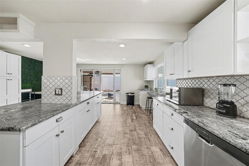 8828 Carmen Lane Port Richey, FL 34668 - Photo 15 of 28 a large kitchen with granite countertop a sink and white cabinets