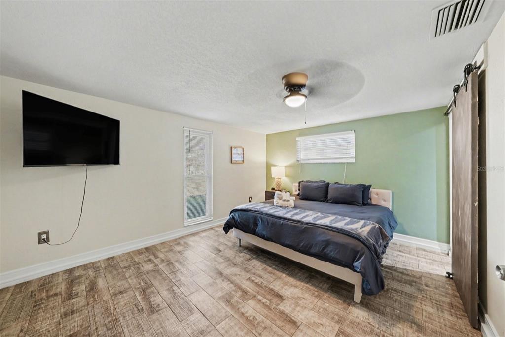 8828 Carmen Lane Port Richey, FL 34668 - Photo 18 of 28 a bedroom with a bed and a flat screen tv