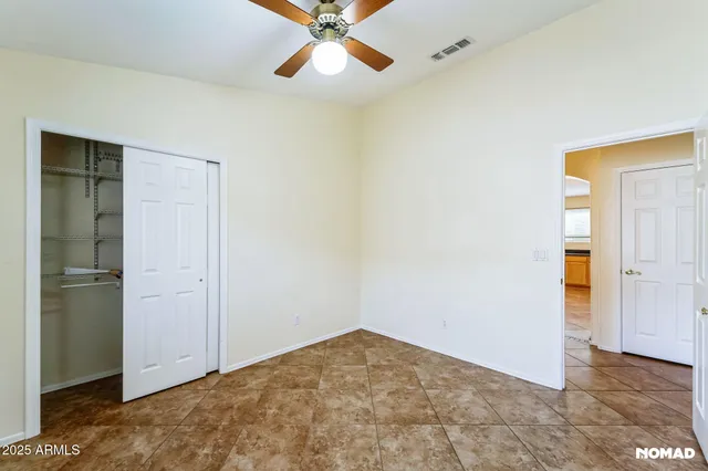 an empty room with closet and a chandelier fan