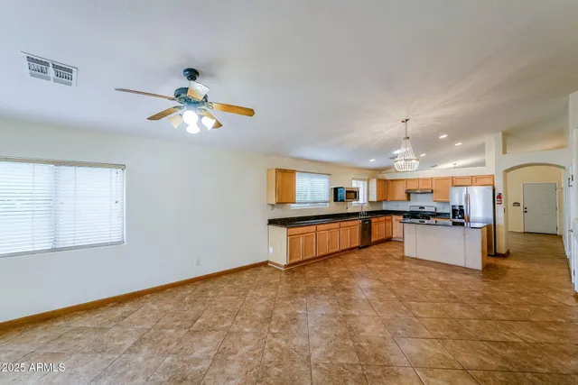 a large kitchen with stainless steel appliances a large counter top a stove and a chandelier