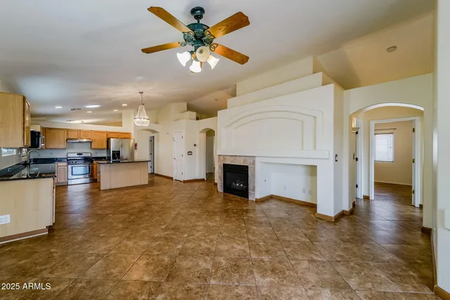 an empty room with fireplace and kitchen view