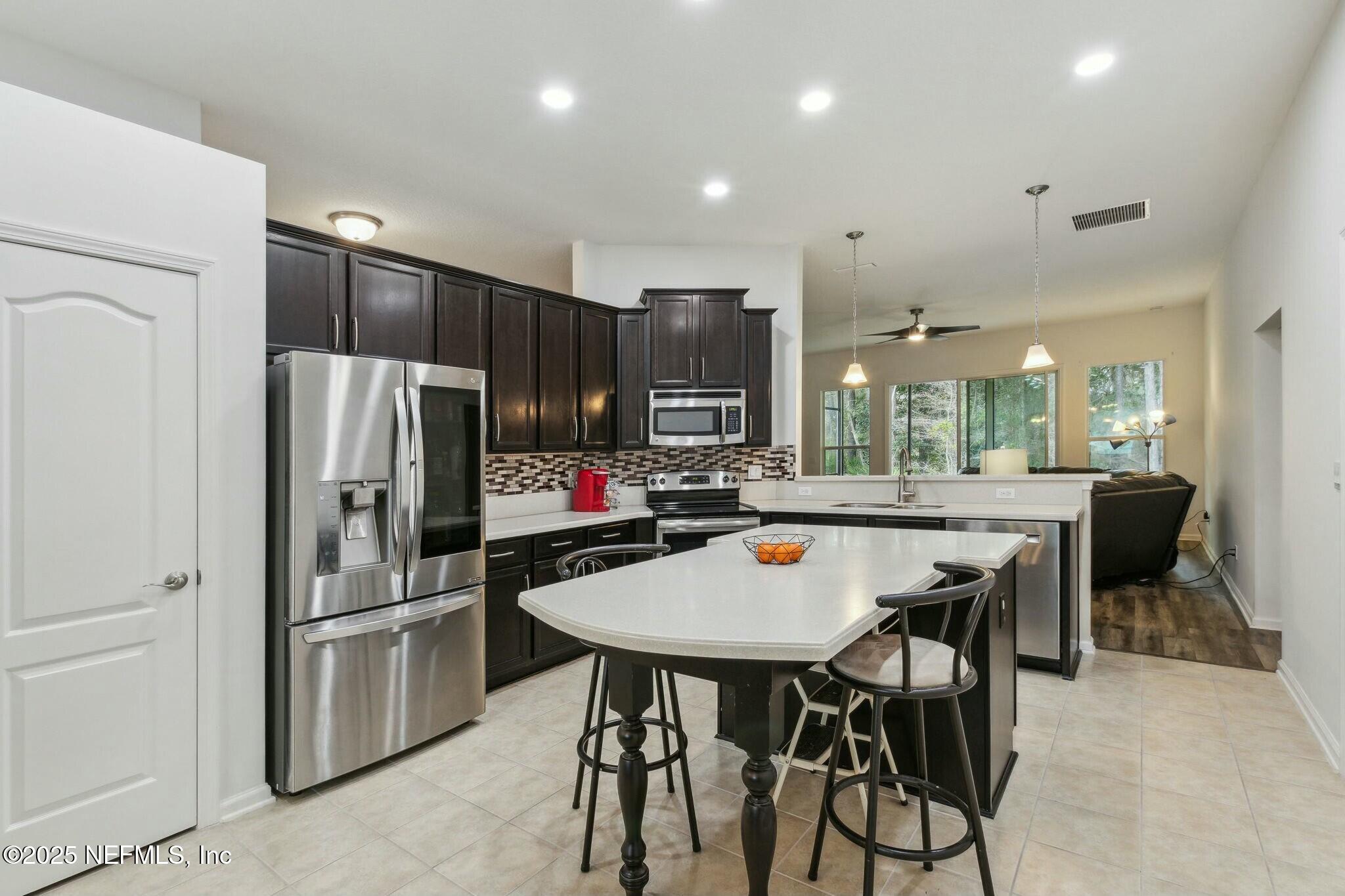 86197 Fortune Drive Yulee, FL 32097 - Photo 7 of 36 a kitchen with stainless steel appliances a dining table chairs refrigerator and cabinets