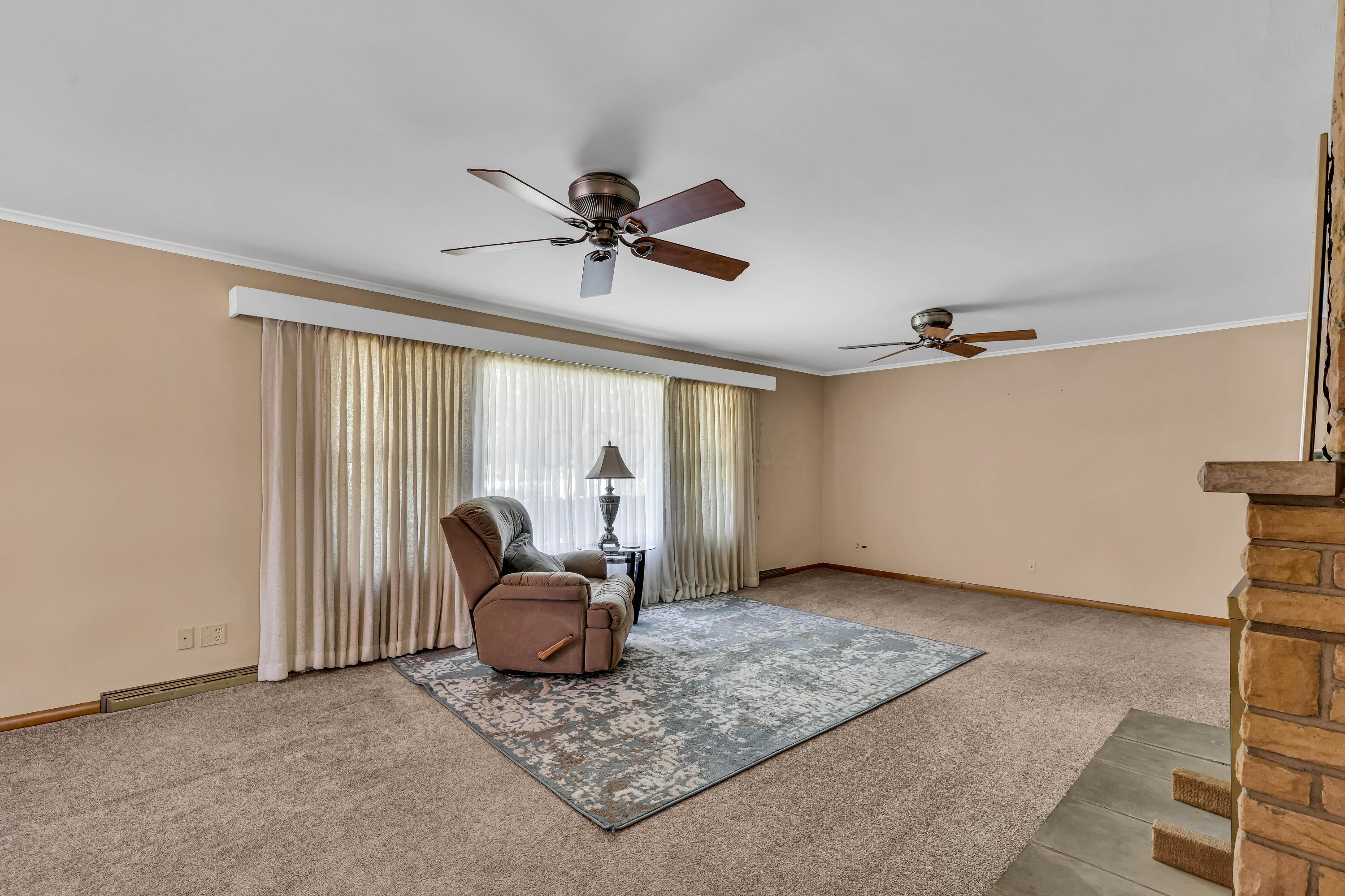 1213 East Cooke Road Columbus, OH 43224 - Photo 11 of 57 • Light sand carpet • Hardwood flooring under carpet • Tan painted walls • (2) ceiling fans • Stone fireplace with raised hearth • Crown molding