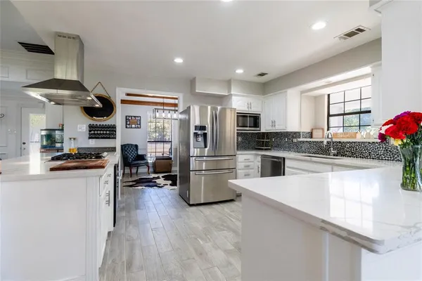 a kitchen with a sink a stove and chairs with wooden floor