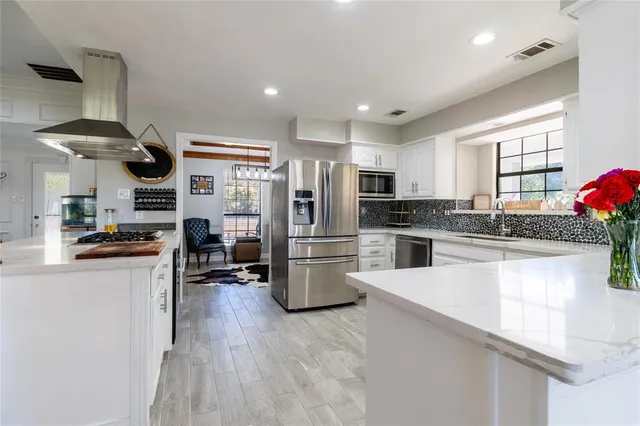 a kitchen with a sink a stove and chairs with wooden floor