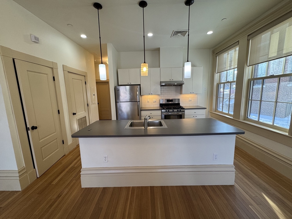 10 Linwood Street, Unit 3 Boston, MA 02119 - Photo 5 of 16 a view of a kitchen with stainless steel appliances granite countertop a sink a refrigerator and wooden floor