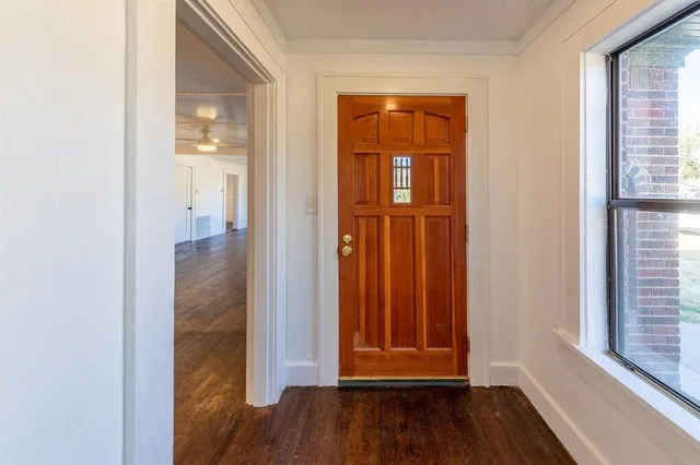 an empty room with wooden floor closet and windows
