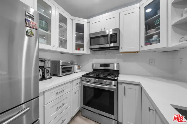 a kitchen with stainless steel appliances white cabinets and a stove top oven