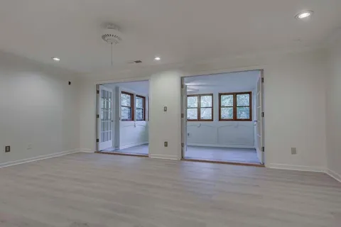 a view of an empty room with wooden floor and windows