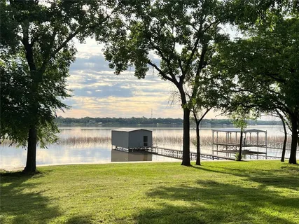 a view of a lake with a big yard and large trees