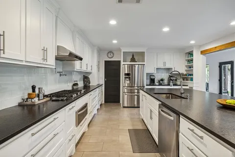 a large kitchen with stainless steel appliances granite countertop a sink and cabinets