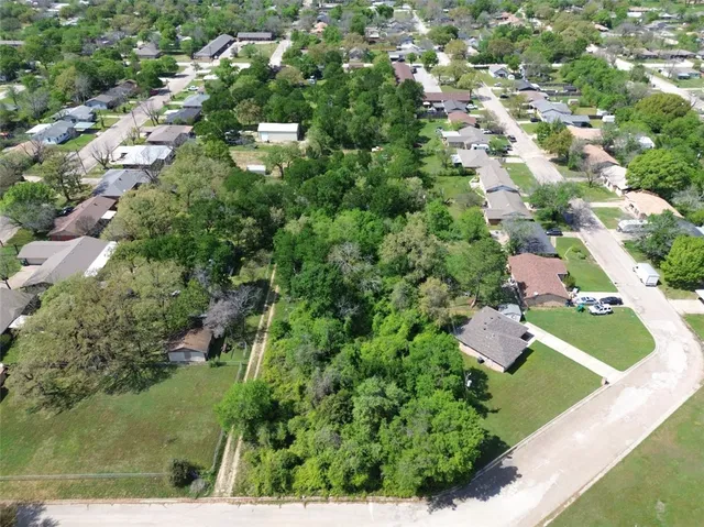 an aerial view of residential houses with outdoor space and trees