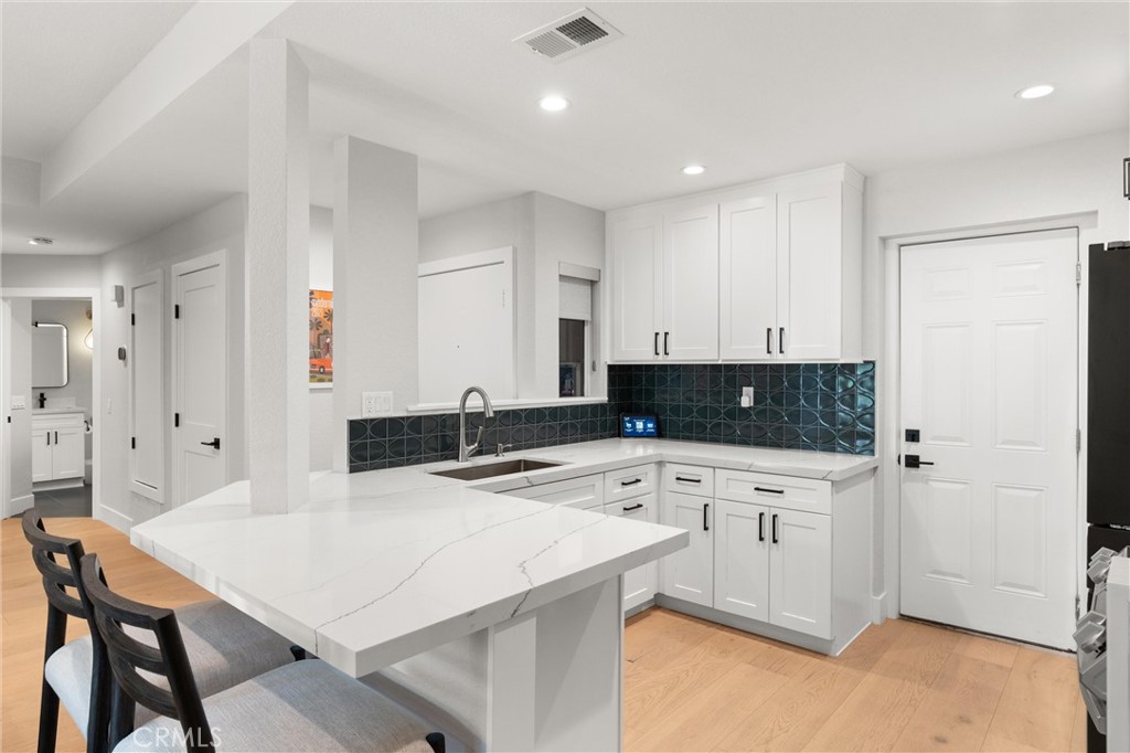 26 Sunbridge Place Dana Point, CA 92629 - Photo 9 of 39 a kitchen with stainless steel appliances a stove a sink a refrigerator and white cabinets with wooden floor