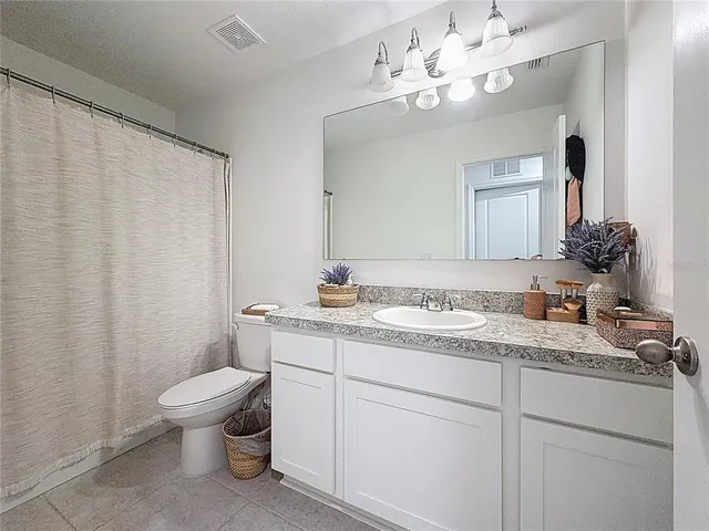 a bathroom with a granite countertop sink a toilet and a mirror