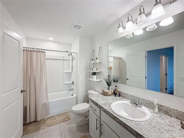 a bathroom with a granite countertop sink a toilet a mirror a vanity and shower