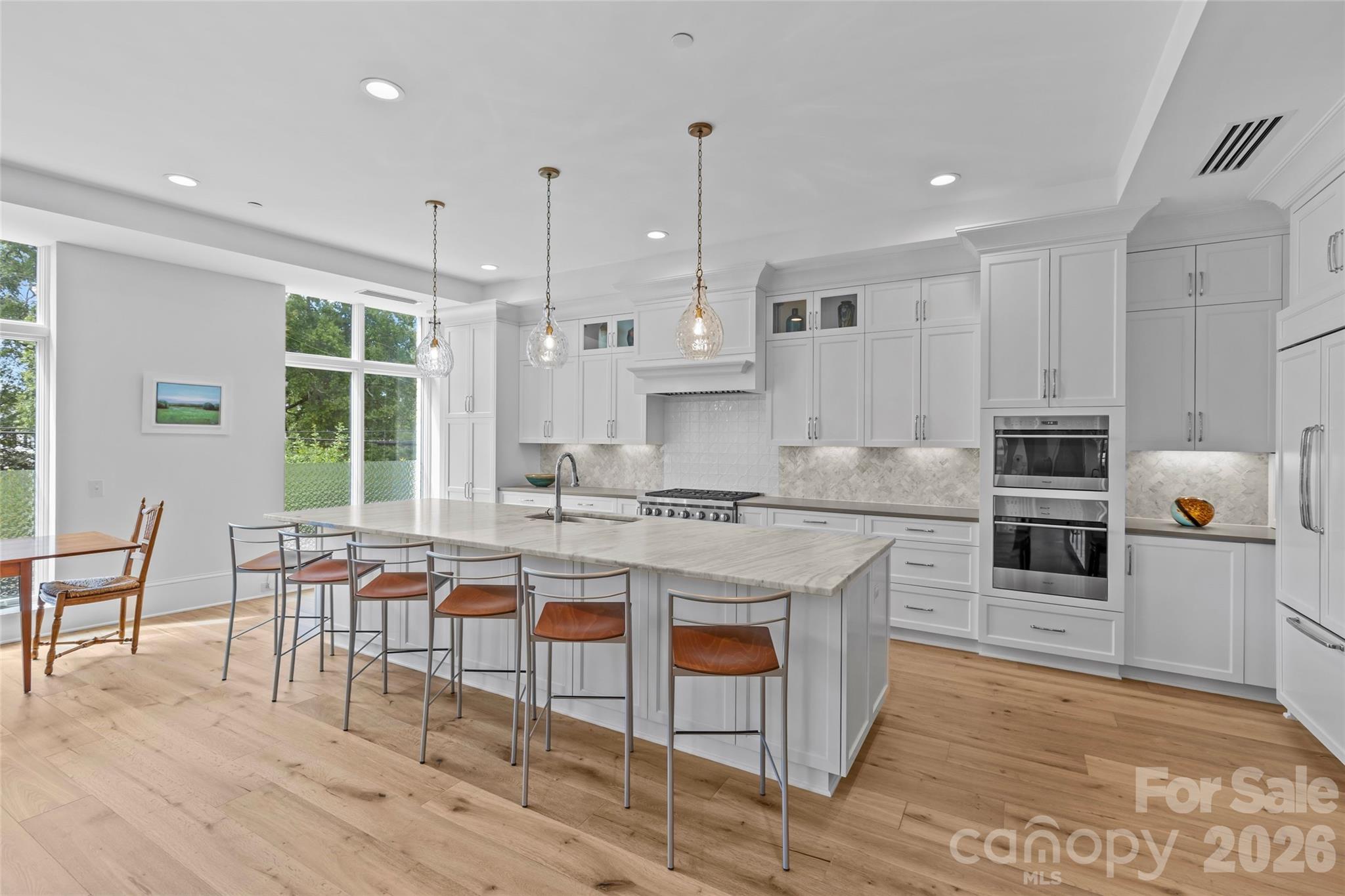 1500 Queens Road, Unit 104 Charlotte, NC 28207 - Photo 5 of 41 a large kitchen with kitchen island a island a stove a table and chairs in it