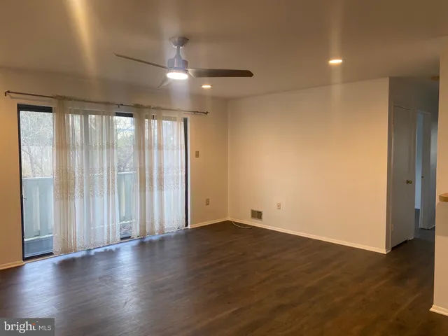 an empty room with wooden floor and windows with curtains