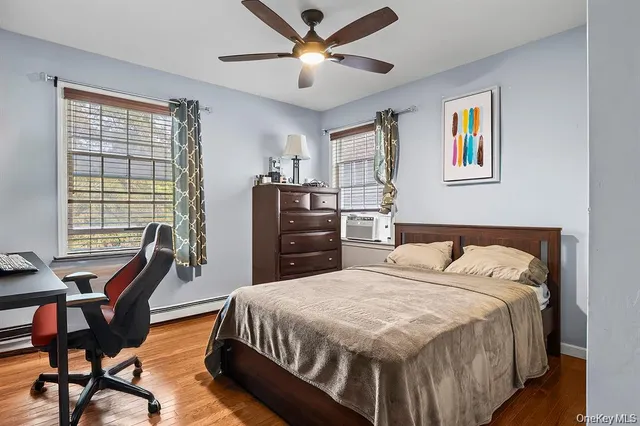 a bedroom with a bed a desk and chair with wooden floor