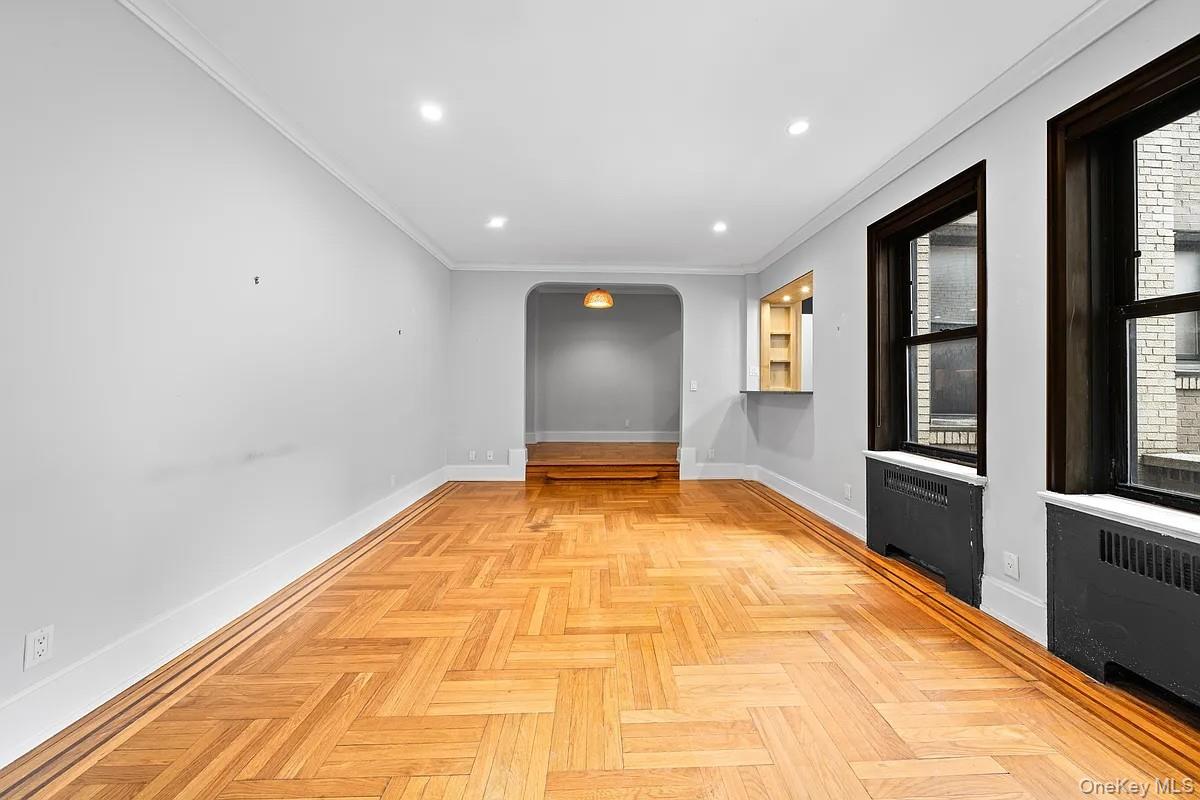 95 Park Terrace East, Unit 1D Manhattan, NY 10034 - Photo 13 of 20 Spare room featuring arched walkways, radiator heating unit, recessed lighting, and crown molding