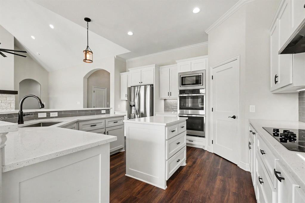 530 P R 491 Leonard, TX 75452 - Photo 12 of 35 Modern kitchen featuring a central island, stainless steel appliances, wood-finish flooring, white cabinetry, and quartz countertops