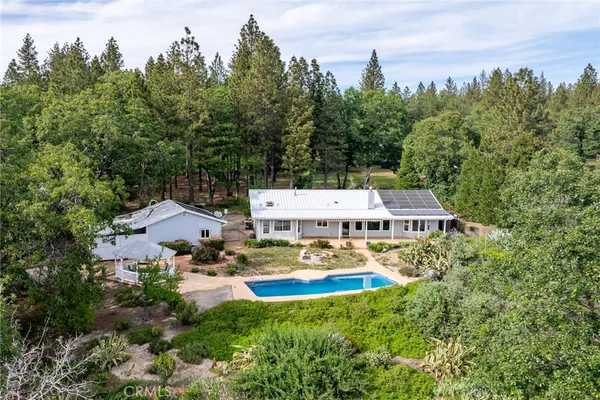 an aerial view of a house with swimming pool and garden
