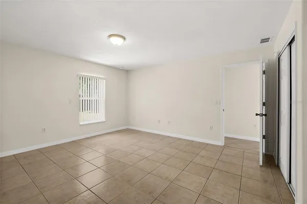 a view of an empty room with window and cabinet area