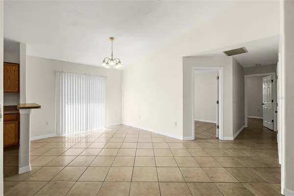 a view of an empty room with a chandelier fan