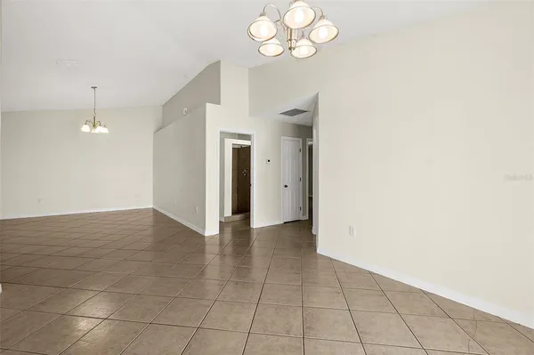 a view of an empty room with a chandelier fan