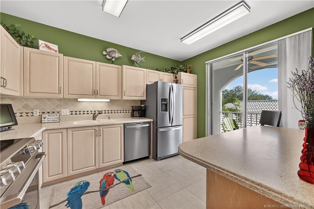 12392 Harbour Ridge Boulevard, Unit 54 Palm City, FL 34990 - Photo 11 of 35 a kitchen with stainless steel appliances granite countertop a refrigerator a sink dishwasher and white cabinets next to a window