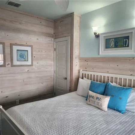 a bedroom with a bed wooden floor and painting on the wall