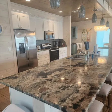 a kitchen with granite countertop a stove a sink and a refrigerator