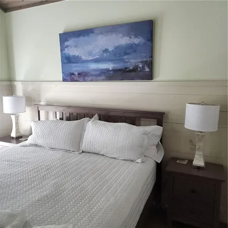 a bedroom with a bed and a lamp on dresser