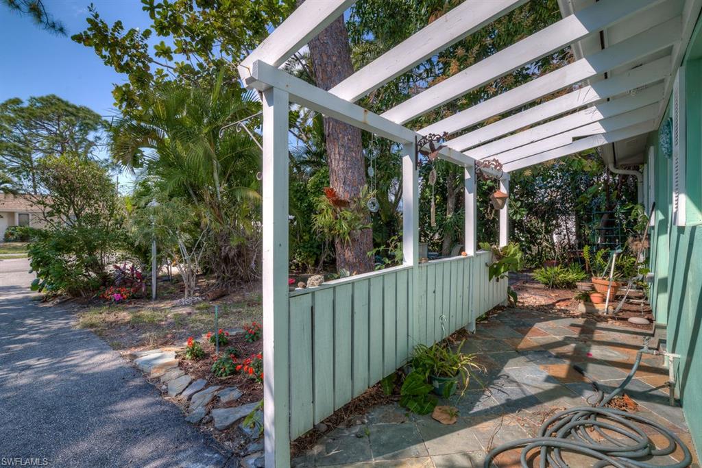9144 7th Street North Naples, FL 34108 - Photo 18 of 20 a view of a patio with table and chairs potted plants with wooden floor and fence