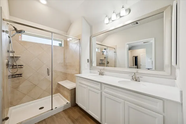 a bathroom with a double vanity sink mirror and shower
