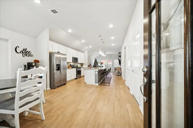 a view of kitchen with stainless steel appliances kitchen island refrigerator stove and wooden floor