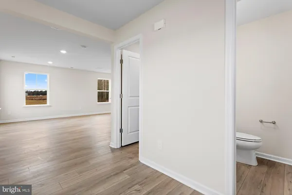 a view of a hallway with wooden floor and a bathroom