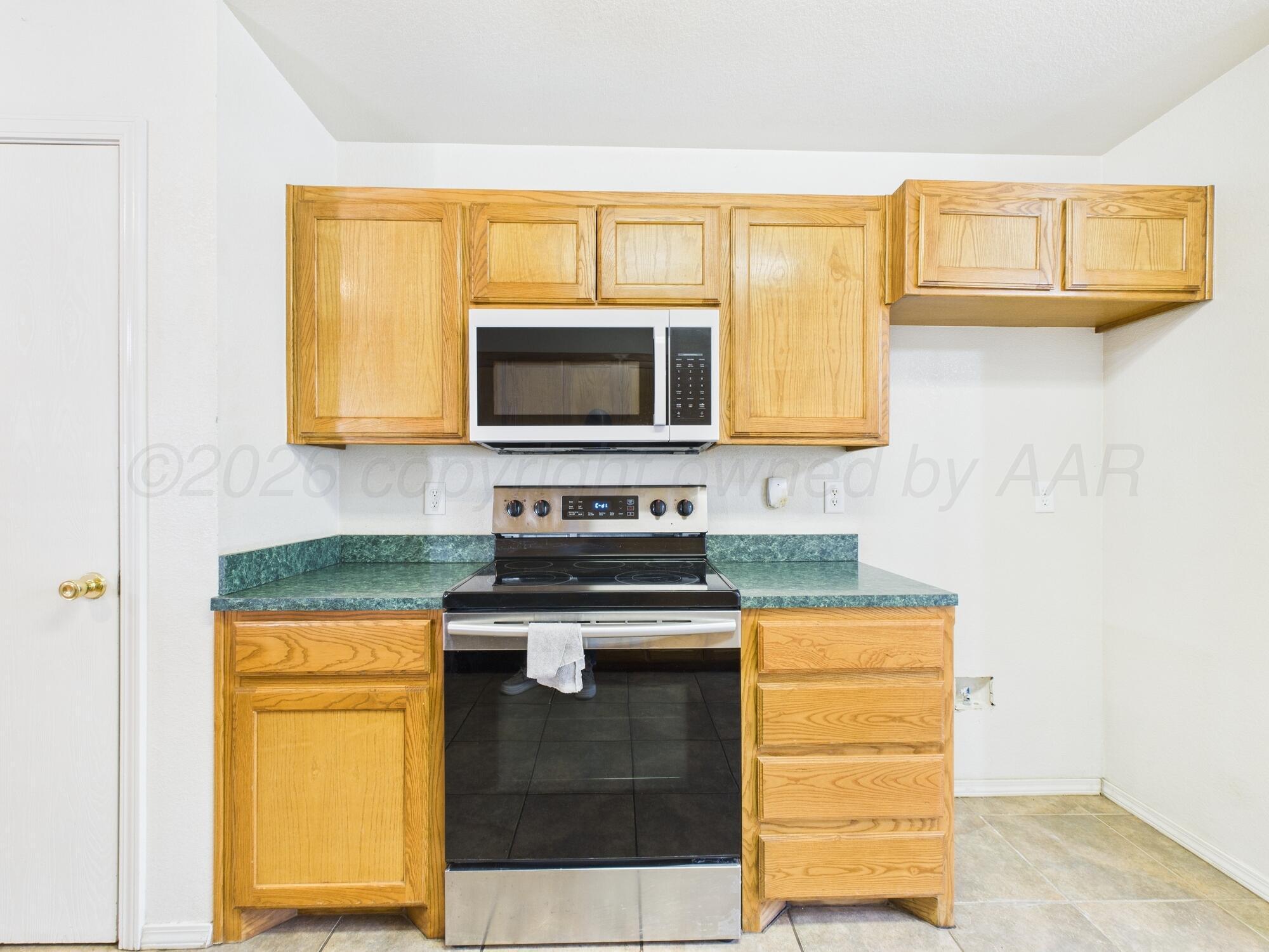 1111 Pikes Peak Drive Amarillo, TX 79110 - Photo 5 of 25 a kitchen with stainless steel appliances granite countertop a stove top oven microwave and cabinets