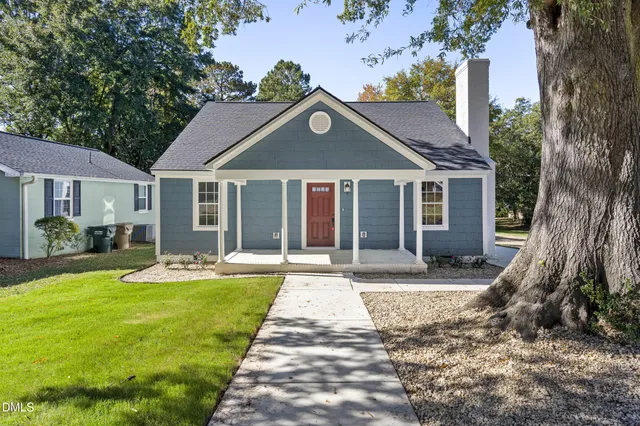 a view of a house with a yard and large tree