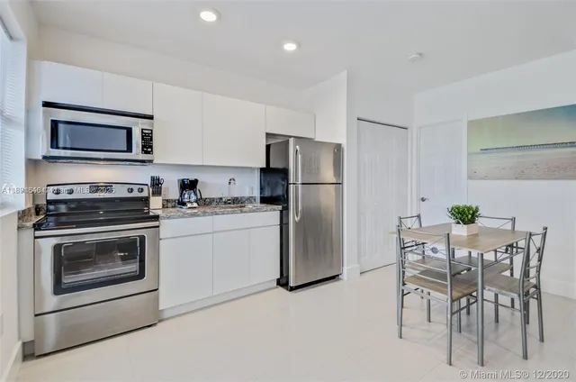 a kitchen with cabinets stainless steel appliances and dining table
