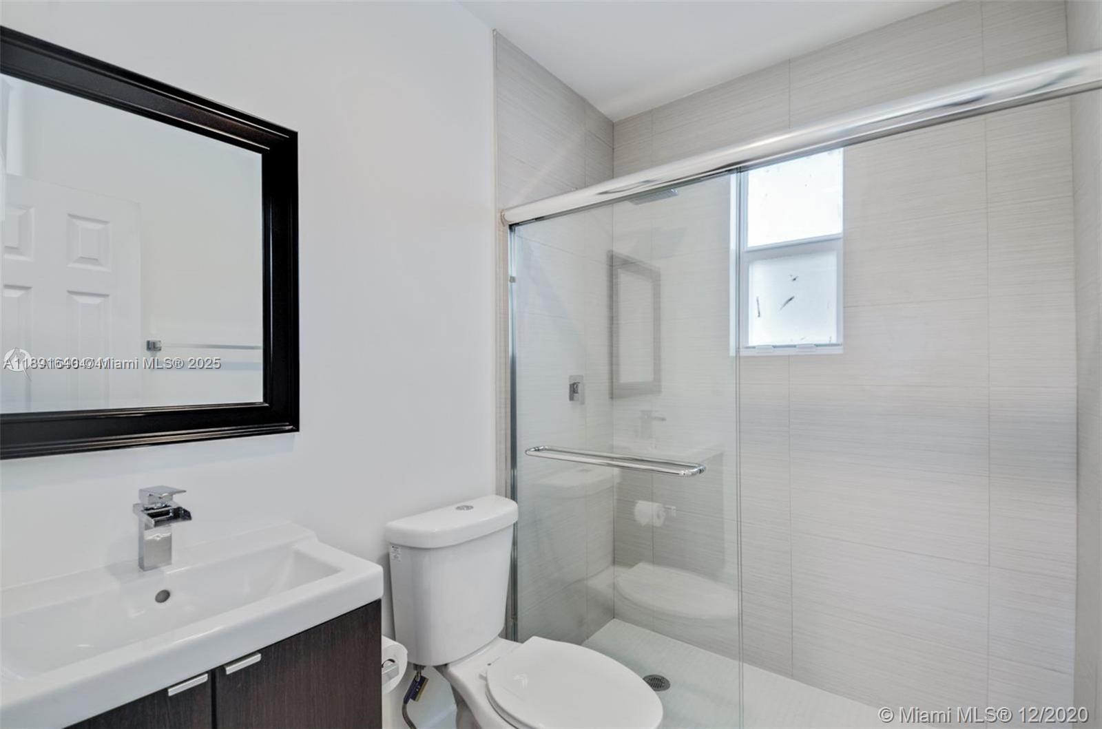 2601 Northwest 1st Avenue, Unit 6 Miami, FL 33127 - Photo 9 of 11 a bathroom with a toilet a sink and mirror