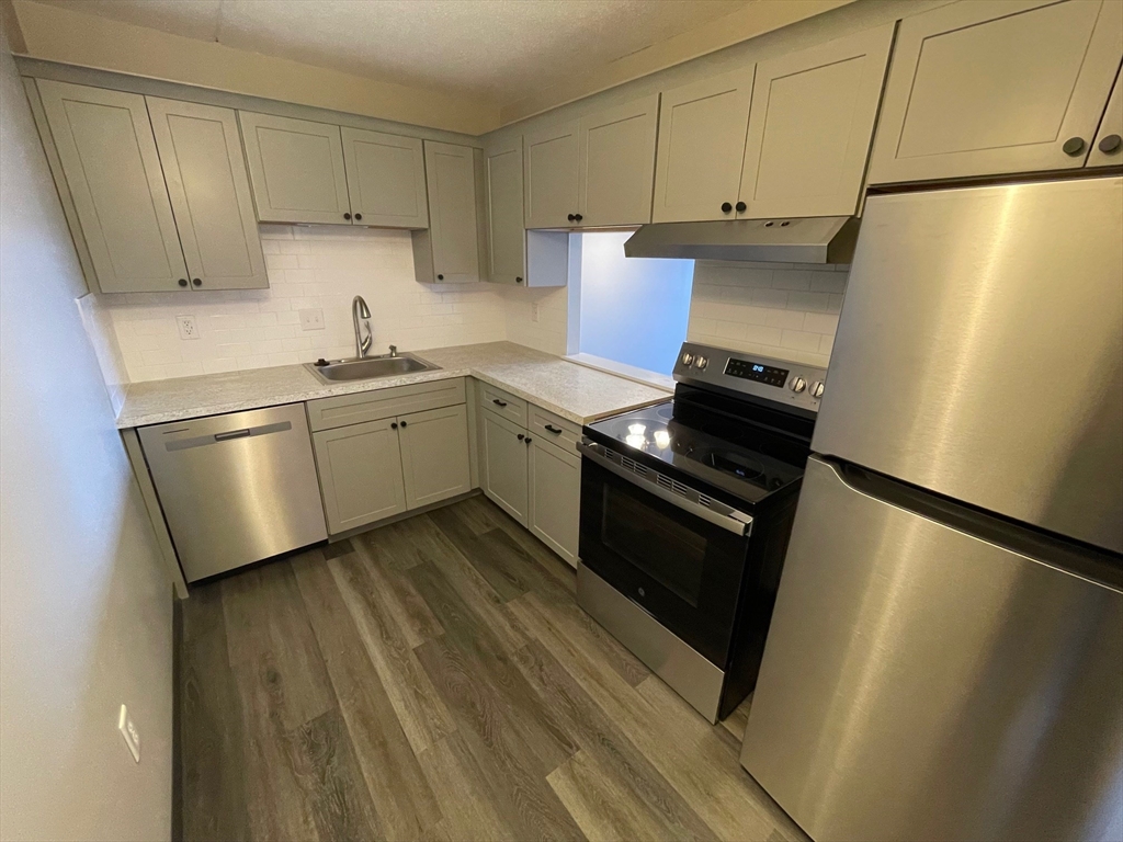 59 Cambridge Road, Unit 108 Woburn, MA 01801 - Photo 5 of 11 a kitchen with a sink a stove and refrigerator