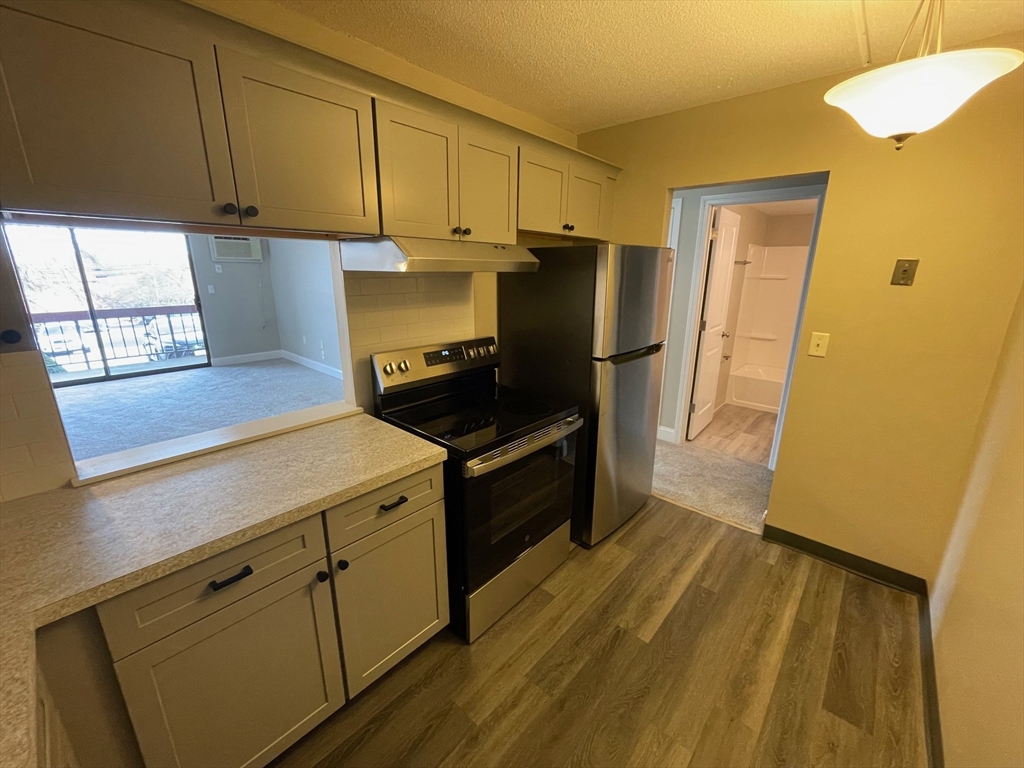59 Cambridge Road, Unit 108 Woburn, MA 01801 - Photo 6 of 11 a kitchen with a refrigerator and a stove top oven