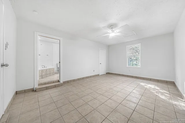 an empty room with windows and fan