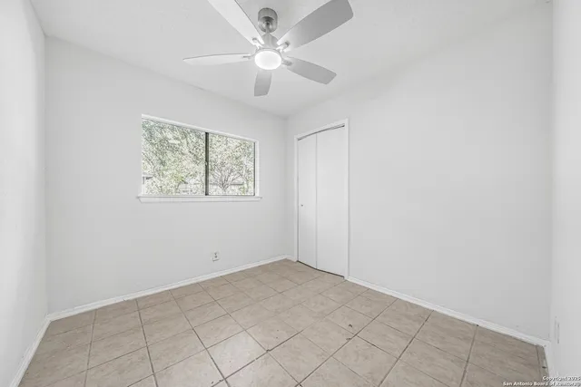 an empty room with windows and fan